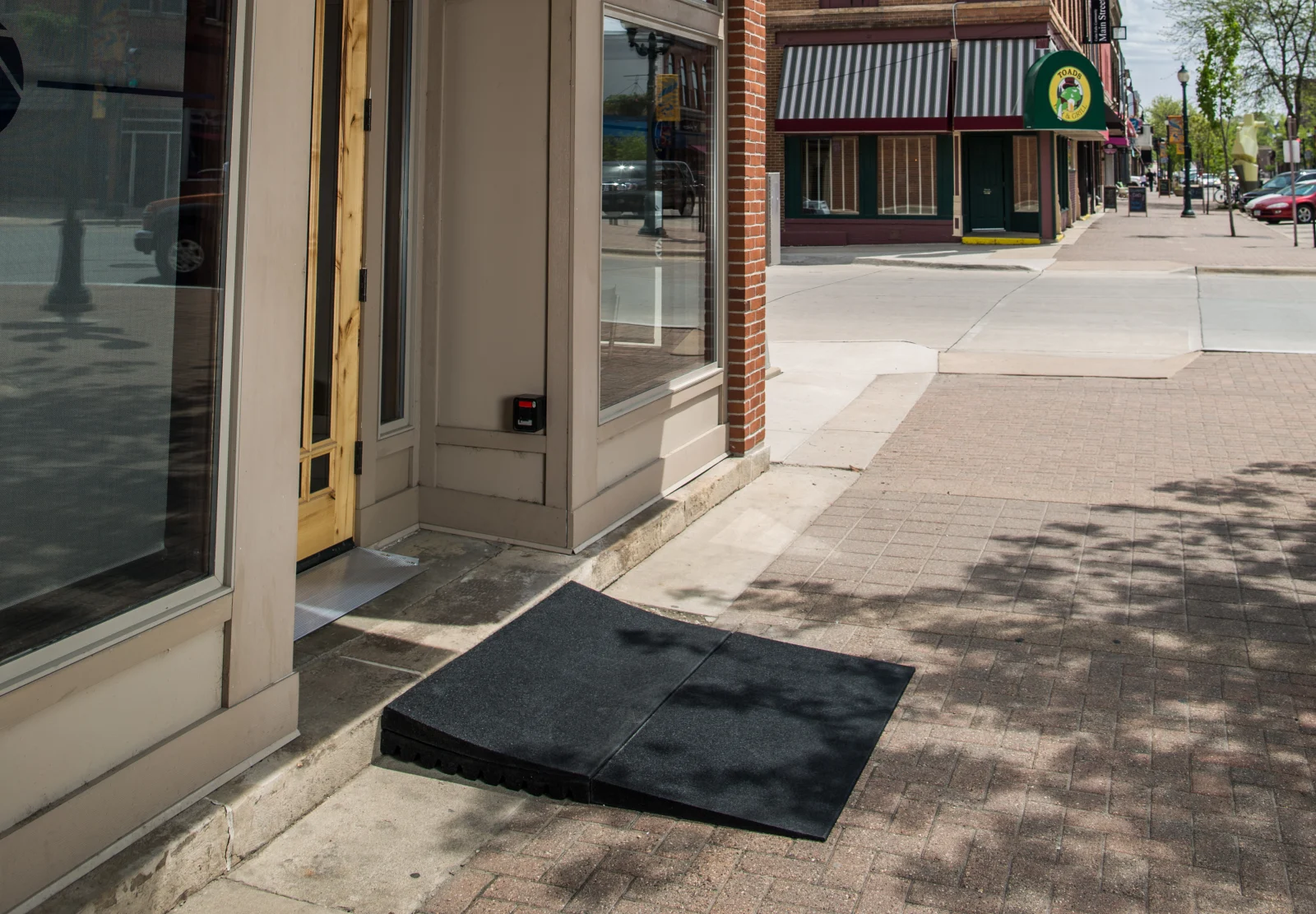 TRANSITIONS rubber threshold ramp bridging the step at a downtown storefront entrance